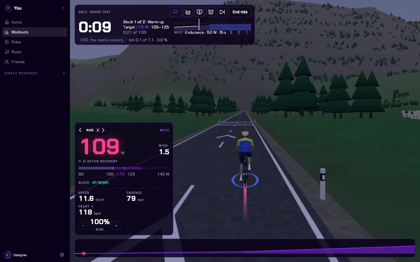 A workout ridden on a mountain road in the 3D world: the next block painted across the road ahead with its target, the workout’s clock and graph above, the bike computer at the left